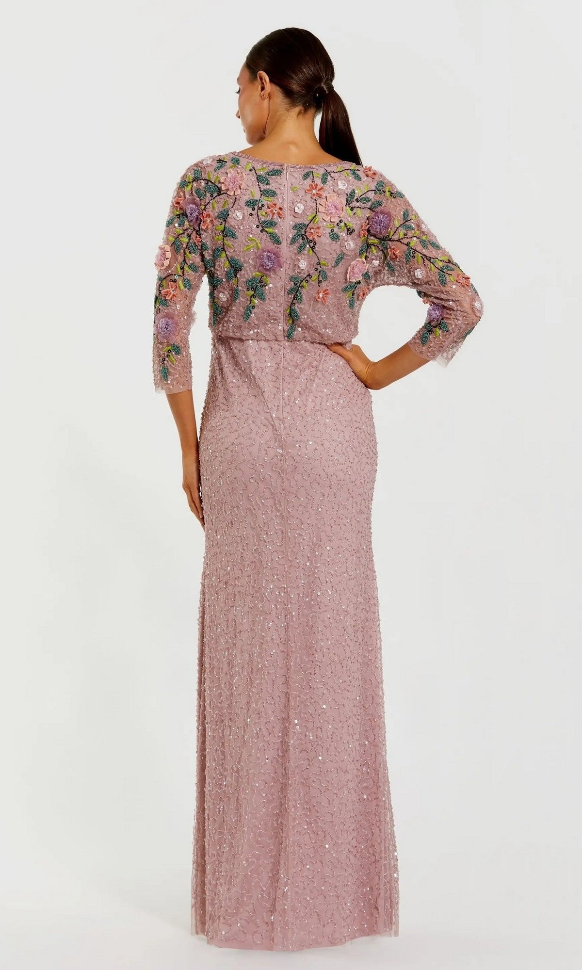 A woman stands with her back to the camera, wearing the Mac Duggal 9341 long formal dress in mauve, featuring floral embroidery and delicate sequin embellishments on the bodice and sleeves.